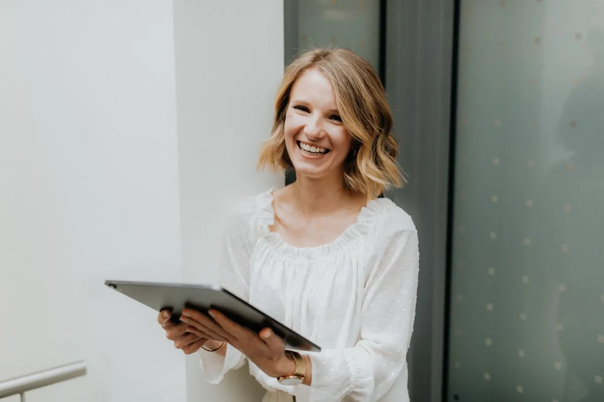 Mitarbeiterin lächelt mit iPad in der Hand
