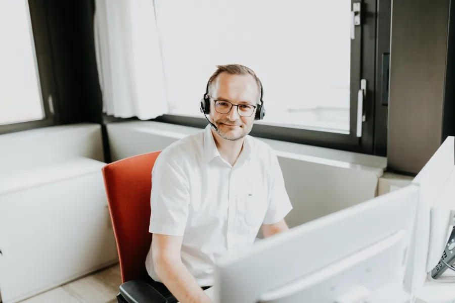 Mitarbeiter sitzt am PC und lächelt