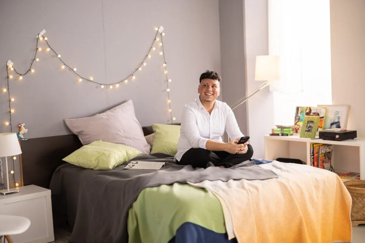 Azubi sitzt lächelnd auf dem Bett und lernt