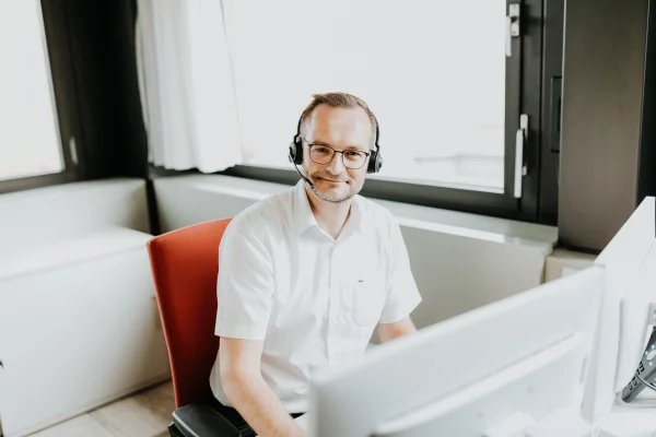 Mitarbeiter sitzt am PC und lächelt