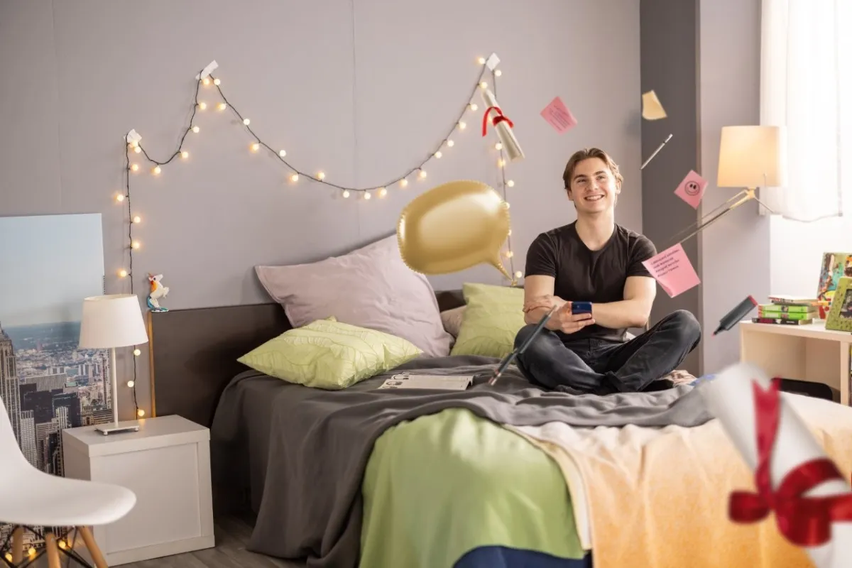 Azubi sitzt lächelnd auf dem Bett und lernt