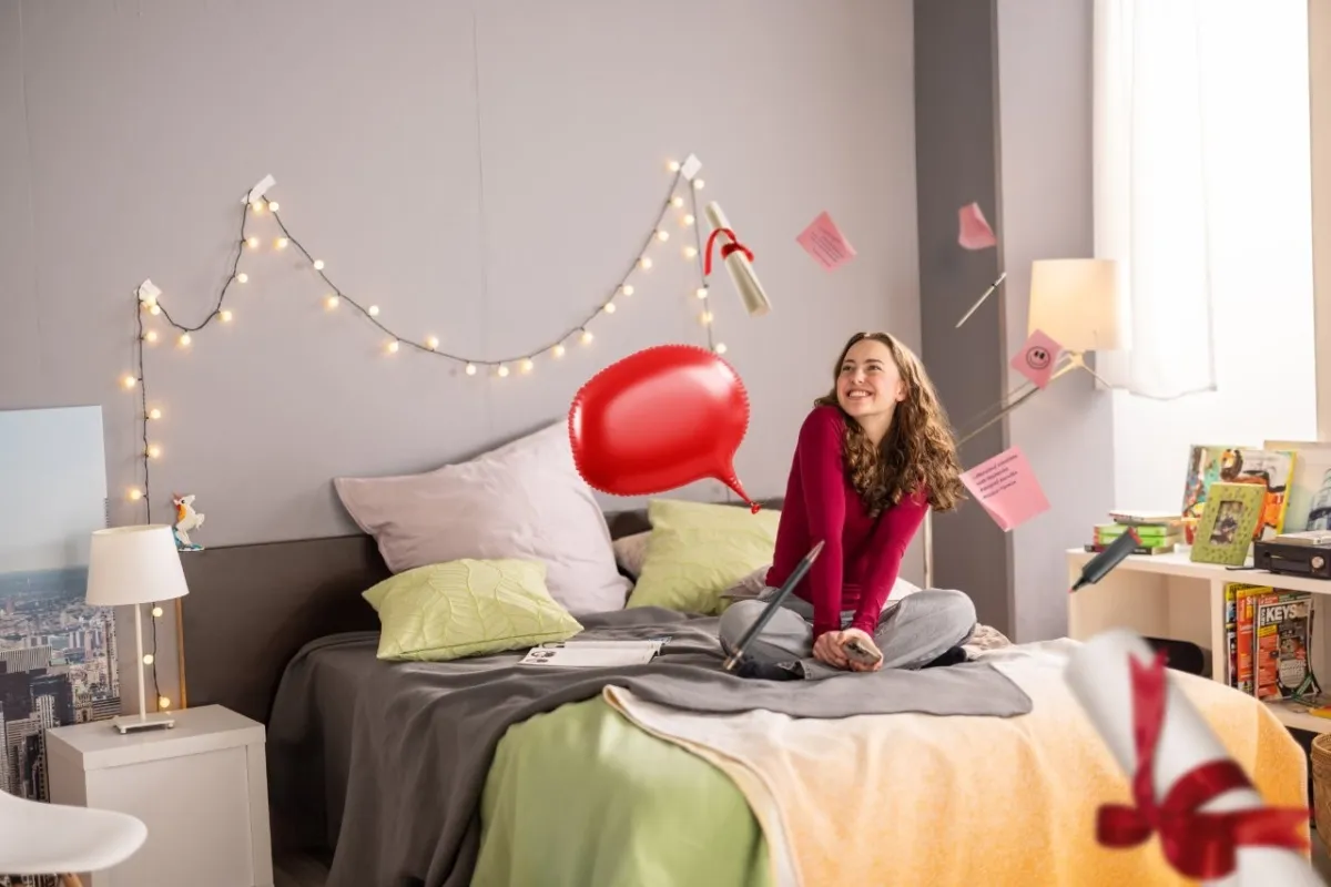 Azubi sitzt lächelnd auf dem Bett und lernt